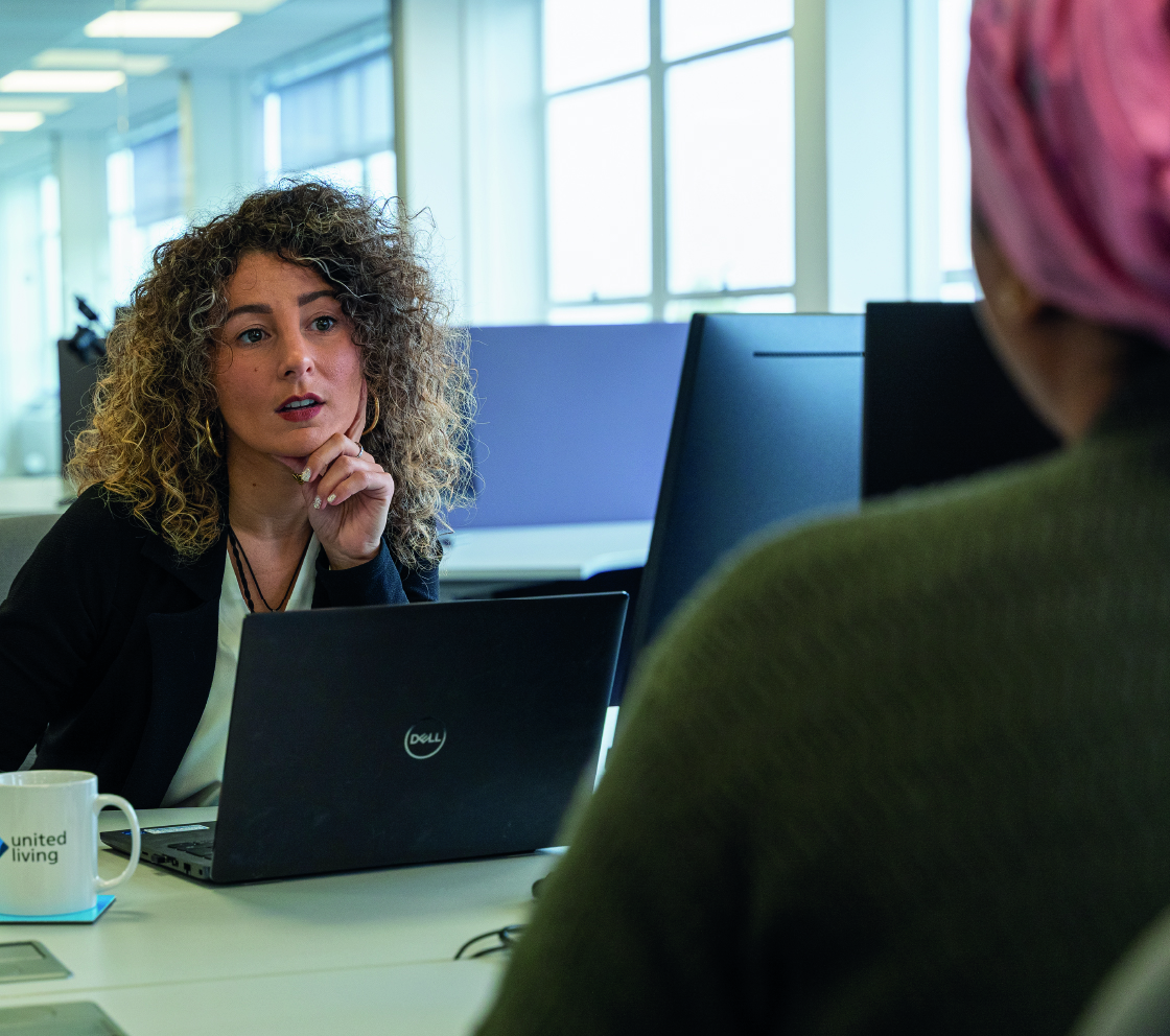 two employees speaking at their desks